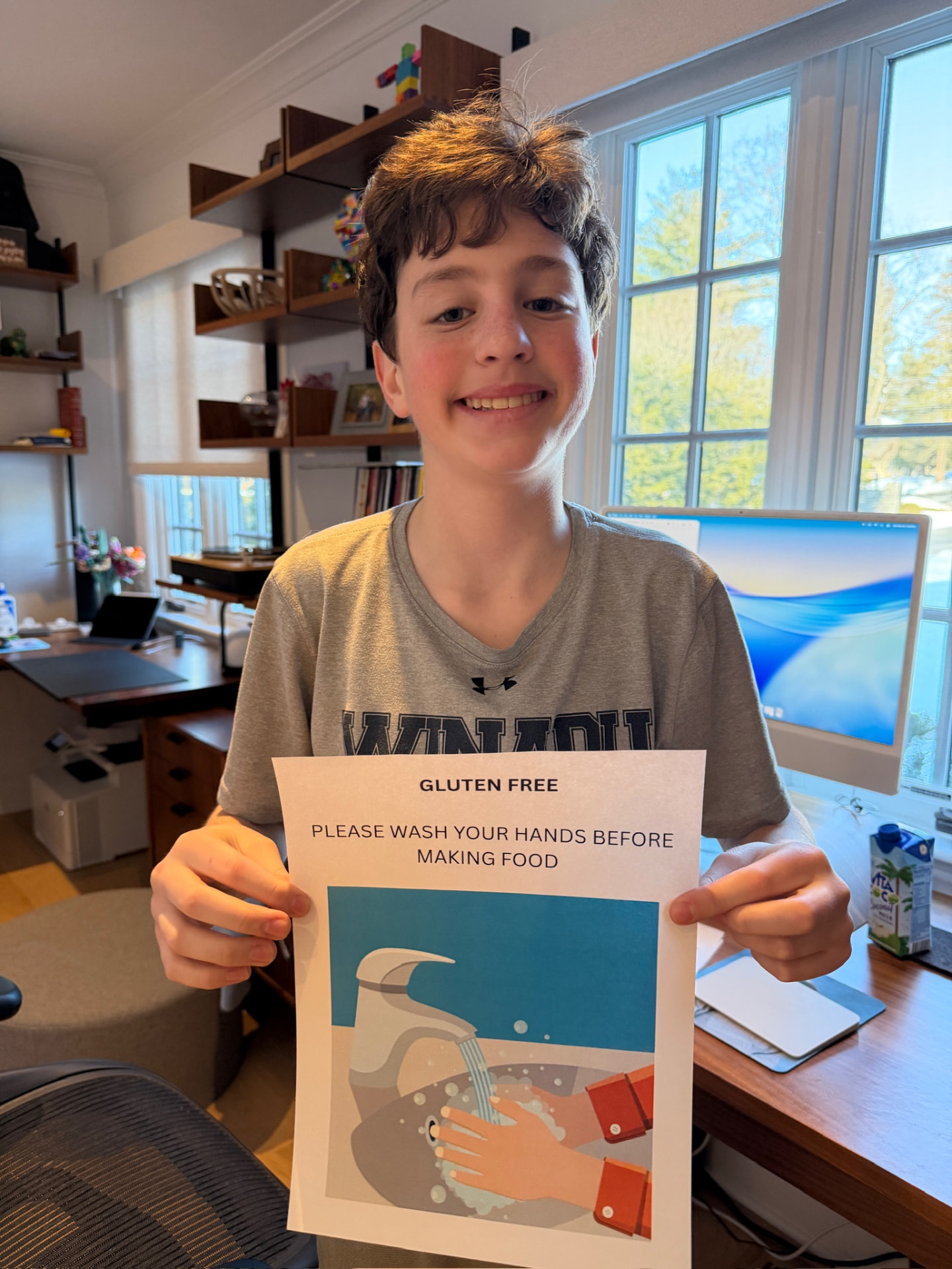 Henry holding the gluten-free hand-washing flyer he designed for the lasagna station