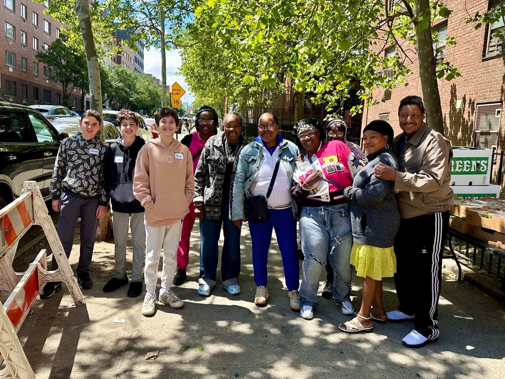Henry and friends with Grassroots Grocery volunteers on a Bronx street beside crates of produce